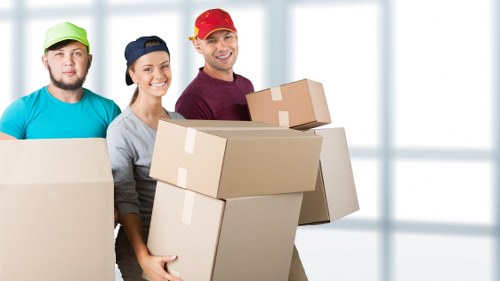 Removal movers carrying furniture through a Fulham home entrance